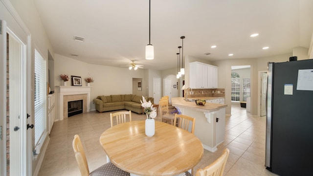 tiled dining space featuring a fireplace, ceiling fan, and sink