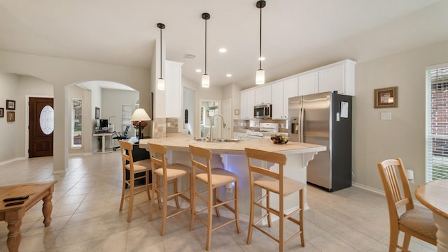 kitchen with white cabinets, sink, appliances with stainless steel finishes, tasteful backsplash, and kitchen peninsula