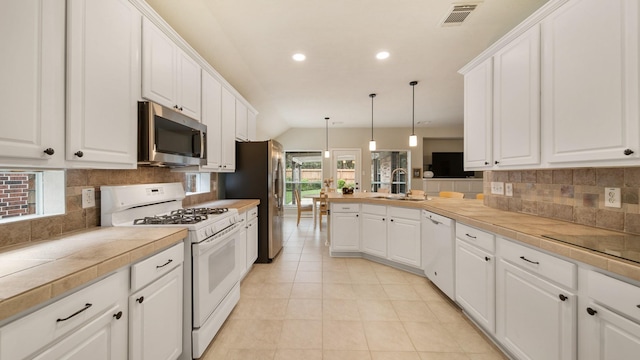 kitchen with a wealth of natural light, pendant lighting, white cabinets, and stainless steel appliances