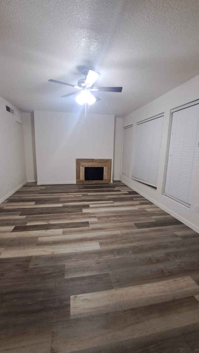 unfurnished living room with ceiling fan, dark hardwood / wood-style flooring, and a textured ceiling