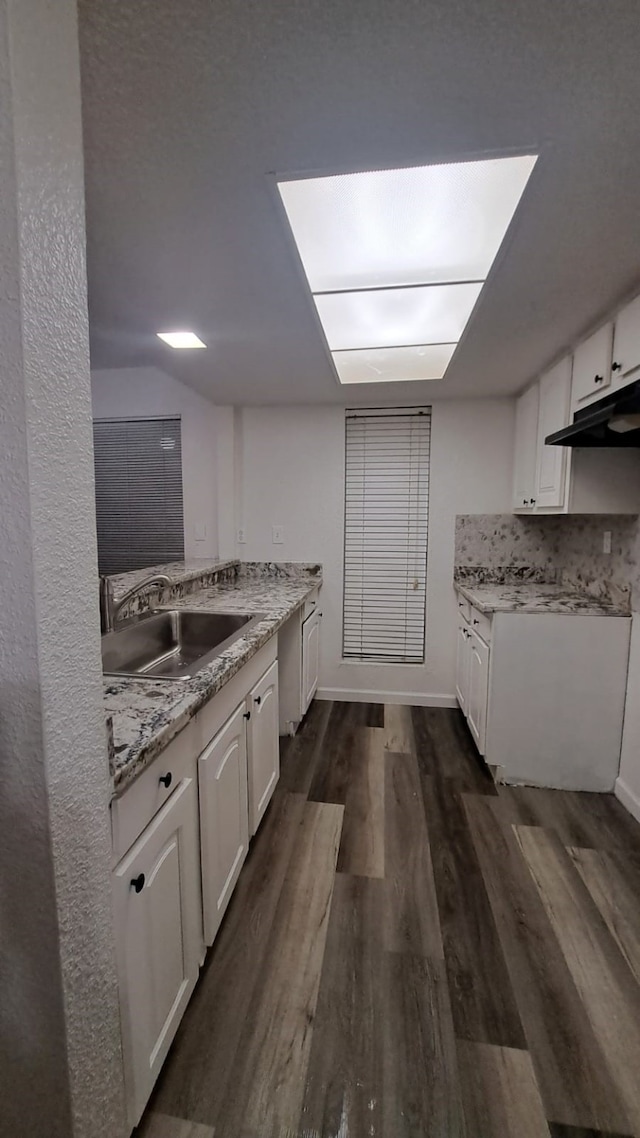 kitchen featuring white cabinets, dark hardwood / wood-style flooring, light stone countertops, and sink