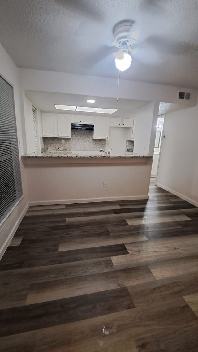 kitchen featuring ceiling fan, dark hardwood / wood-style floors, kitchen peninsula, decorative backsplash, and white cabinets