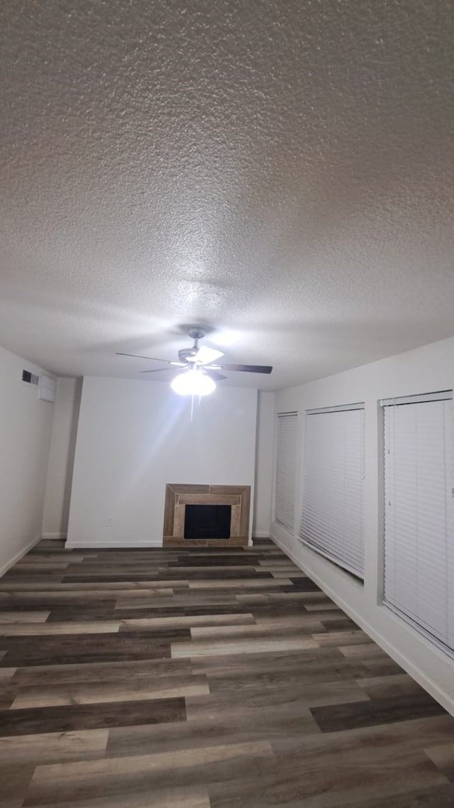 unfurnished living room featuring ceiling fan, dark hardwood / wood-style flooring, and a textured ceiling