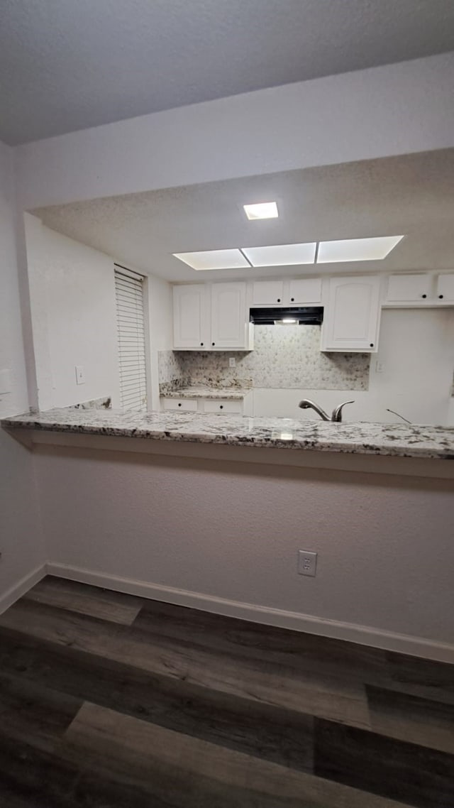 kitchen with light stone counters, white cabinetry, dark wood-type flooring, and tasteful backsplash