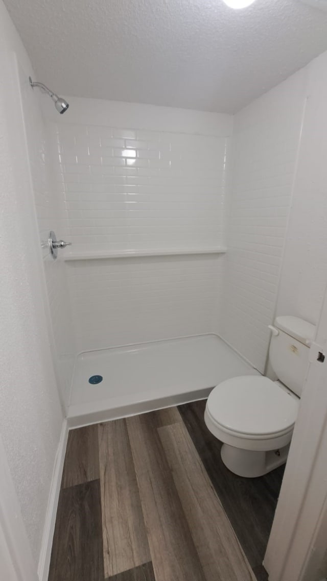 bathroom with a textured ceiling, wood-type flooring, and walk in shower