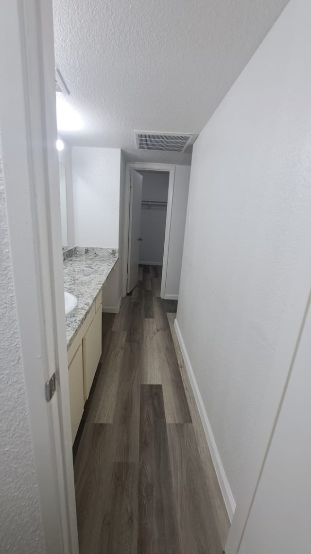 hall with a textured ceiling and dark wood-type flooring