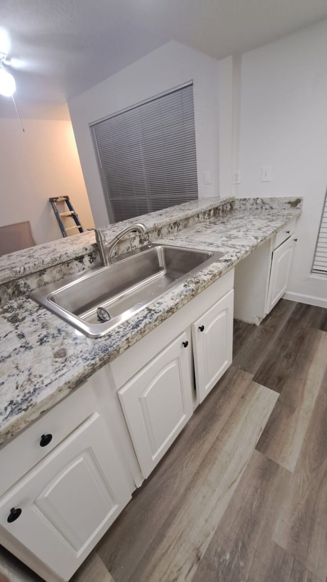 kitchen with dark wood-type flooring, white cabinets, sink, ceiling fan, and light stone counters