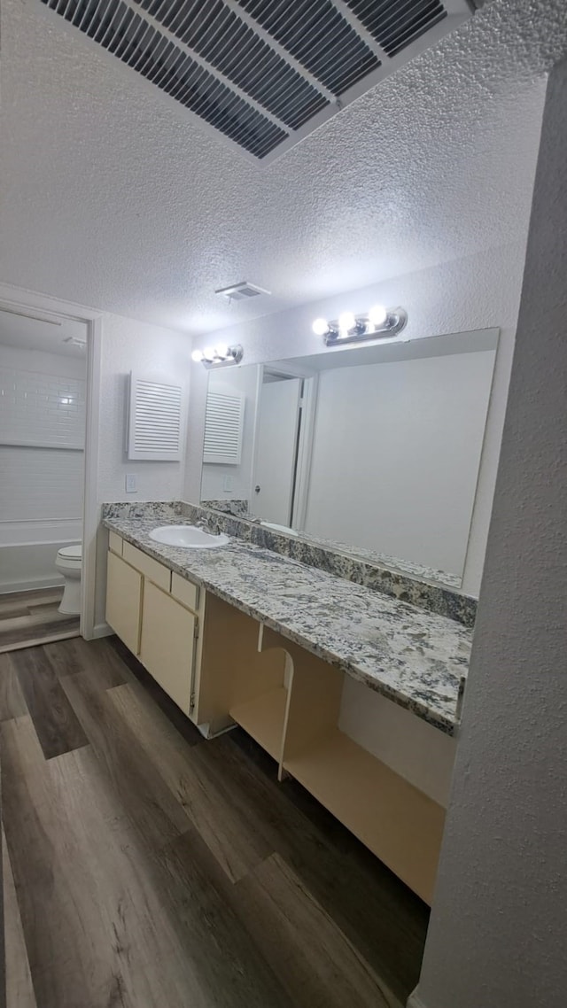 full bathroom featuring a textured ceiling, toilet, vanity, bathtub / shower combination, and hardwood / wood-style flooring