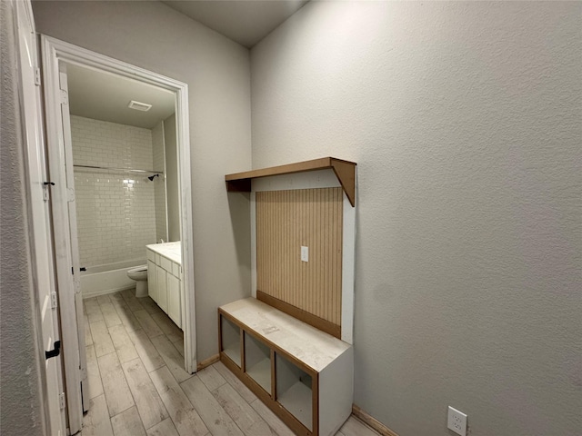 full bathroom featuring hardwood / wood-style flooring, vanity, tiled shower / bath combo, and toilet