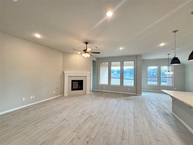 unfurnished living room with ceiling fan, light hardwood / wood-style flooring, and a textured ceiling