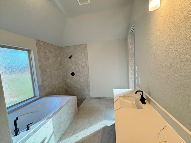 bathroom featuring lofted ceiling, tile patterned flooring, vanity, and tiled tub