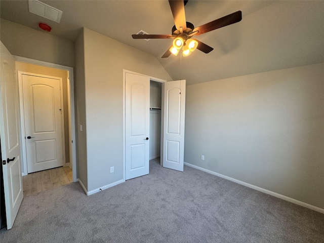 unfurnished bedroom featuring ceiling fan, light colored carpet, lofted ceiling, and a closet