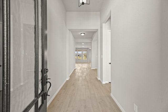 corridor with light wood-style flooring and baseboards