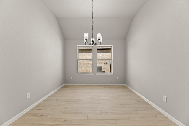 unfurnished dining area with lofted ceiling, light wood-style floors, baseboards, and a notable chandelier