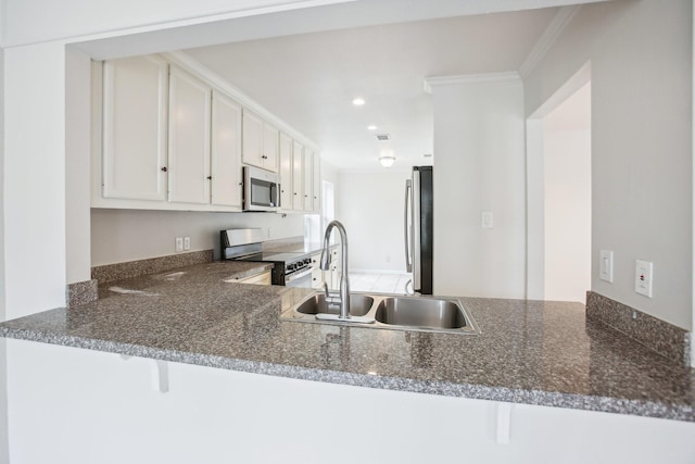 kitchen with crown molding, sink, appliances with stainless steel finishes, white cabinetry, and kitchen peninsula