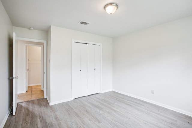 unfurnished bedroom with light hardwood / wood-style floors and a closet