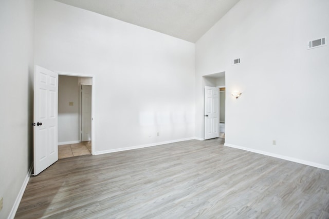 unfurnished room featuring light wood-type flooring and high vaulted ceiling