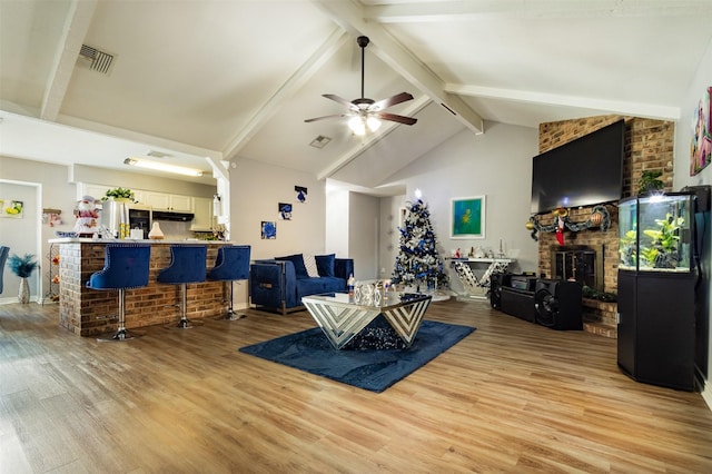 living room with a fireplace, ceiling fan, light hardwood / wood-style flooring, and lofted ceiling with beams