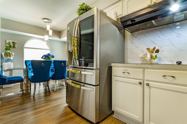 kitchen with stainless steel fridge, white cabinets, and light wood-type flooring