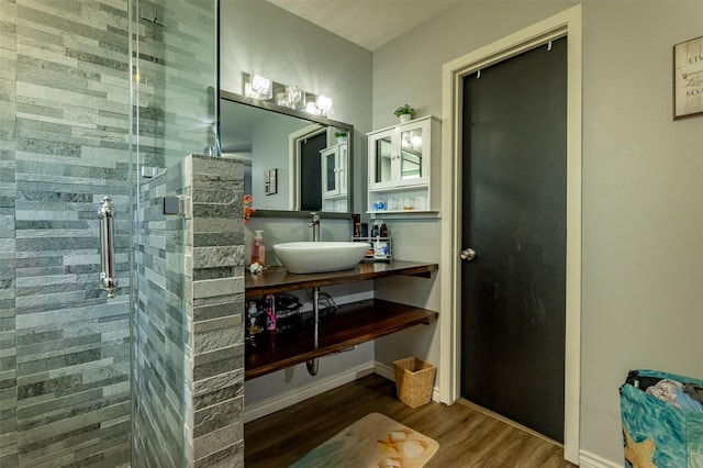 bathroom with a tile shower, vanity, and hardwood / wood-style flooring