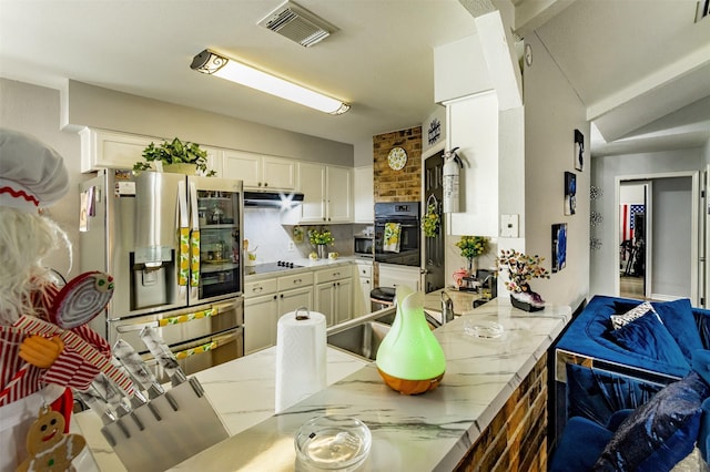 kitchen featuring vaulted ceiling, tasteful backsplash, light stone counters, kitchen peninsula, and stainless steel appliances