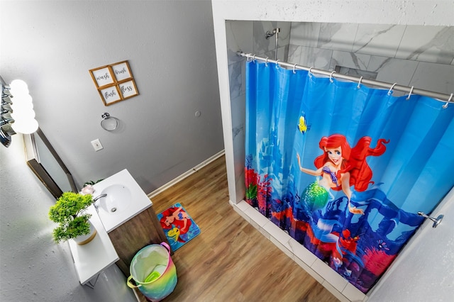 interior space with a shower with shower curtain, hardwood / wood-style floors, and vanity