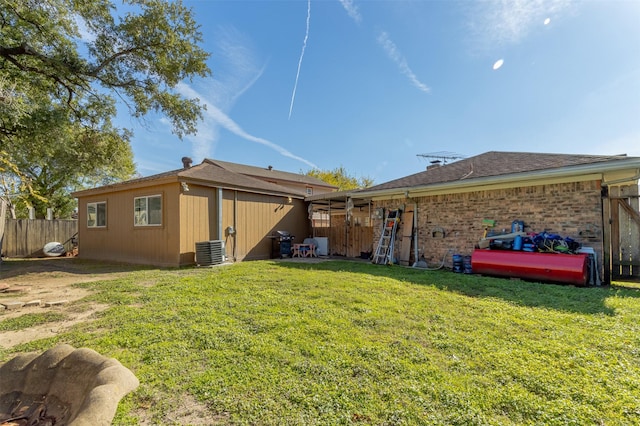 back of house with central AC and a yard