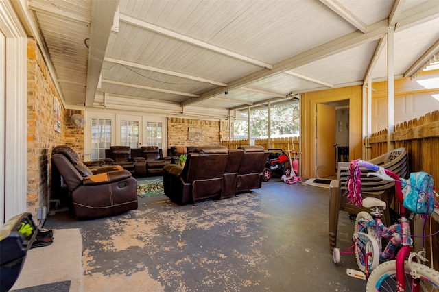 living room featuring concrete flooring, a healthy amount of sunlight, and brick wall