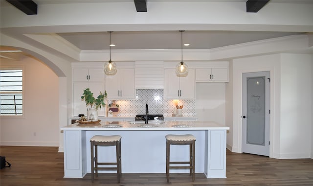 kitchen featuring a breakfast bar area, a kitchen island with sink, and white cabinets