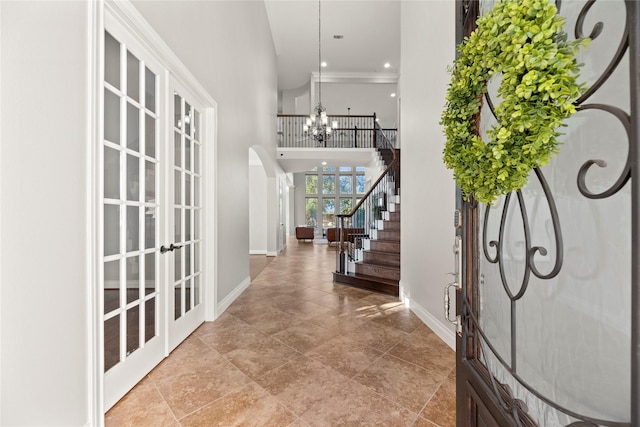 foyer entrance featuring french doors, a high ceiling, and an inviting chandelier