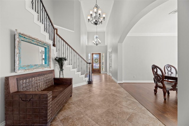 foyer entrance featuring a chandelier, wood-type flooring, a towering ceiling, and ornamental molding