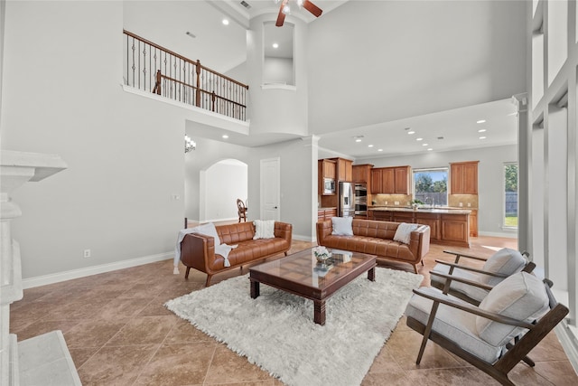 living room featuring a high ceiling, ceiling fan, and light tile patterned flooring