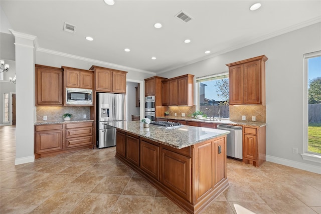 kitchen with appliances with stainless steel finishes, a center island, a wealth of natural light, and a notable chandelier