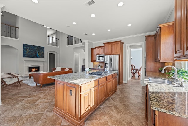 kitchen with light stone countertops, sink, a center island, stainless steel appliances, and crown molding