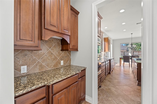 kitchen featuring stone counters, hanging light fixtures, tasteful backsplash, a notable chandelier, and light tile patterned flooring