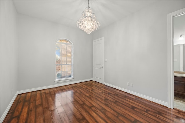 spare room with a notable chandelier and dark wood-type flooring