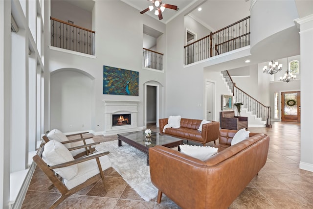 tiled living room featuring a high ceiling and ceiling fan with notable chandelier