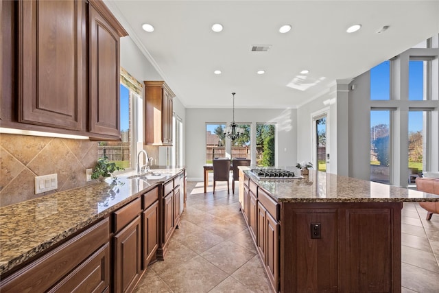 kitchen with pendant lighting, a notable chandelier, a healthy amount of sunlight, and sink