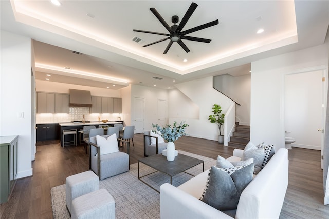 living room featuring ceiling fan, a tray ceiling, and wood finished floors