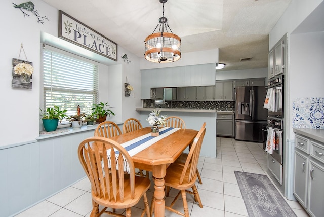 tiled dining area featuring wooden walls, sink, a textured ceiling, and a notable chandelier