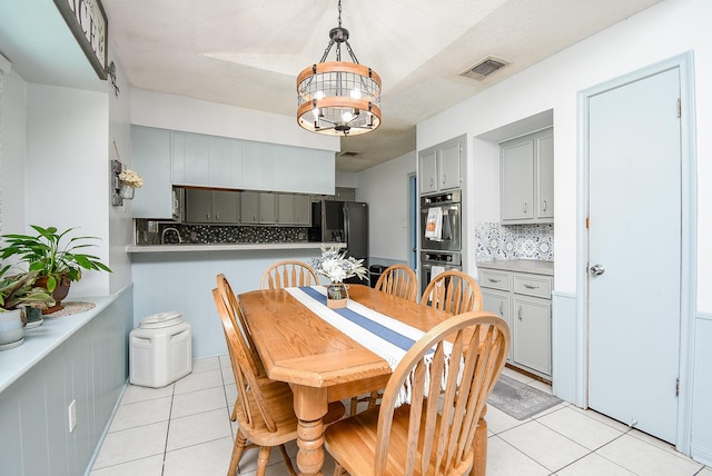 tiled dining area with a textured ceiling and a chandelier