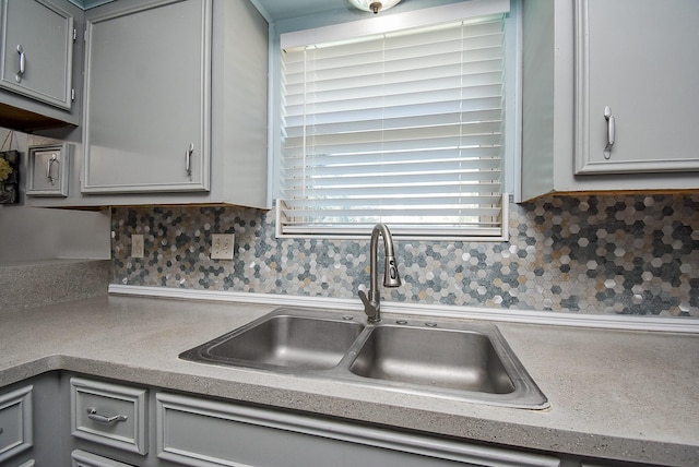 kitchen featuring tasteful backsplash, gray cabinetry, and sink