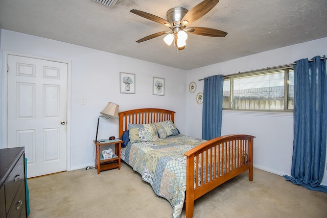 bedroom featuring ceiling fan, light colored carpet, and a textured ceiling