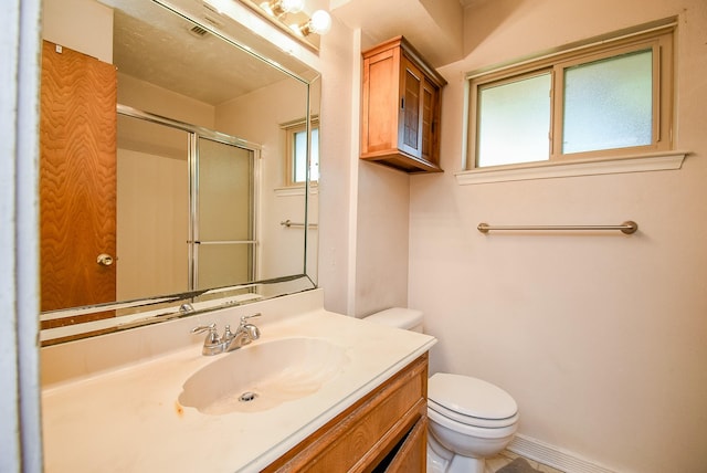 bathroom featuring vanity, toilet, walk in shower, and a healthy amount of sunlight