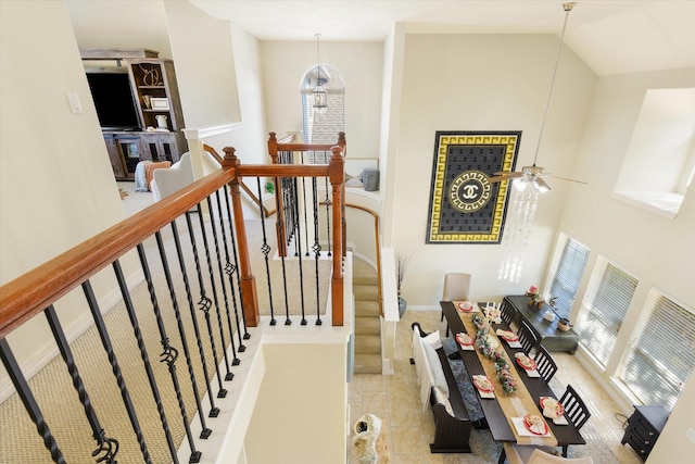 stairs with ceiling fan with notable chandelier, high vaulted ceiling, and a wealth of natural light