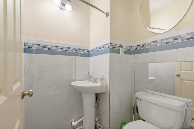 bathroom featuring sink, toilet, and tile walls