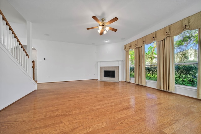 unfurnished living room with light hardwood / wood-style floors, ceiling fan, and a tiled fireplace