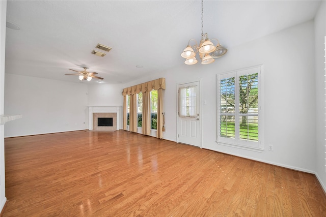 unfurnished living room featuring ceiling fan with notable chandelier and light hardwood / wood-style floors