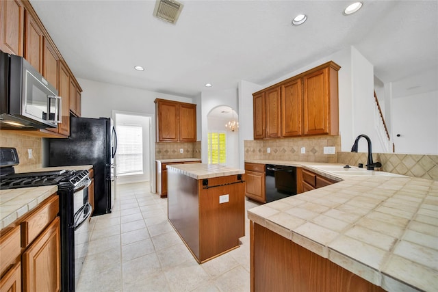 kitchen with black appliances, a kitchen island, sink, and tile countertops