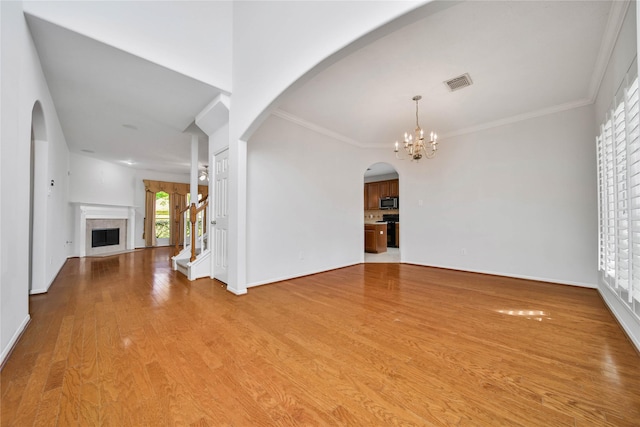 unfurnished living room with a chandelier, light hardwood / wood-style flooring, and ornamental molding